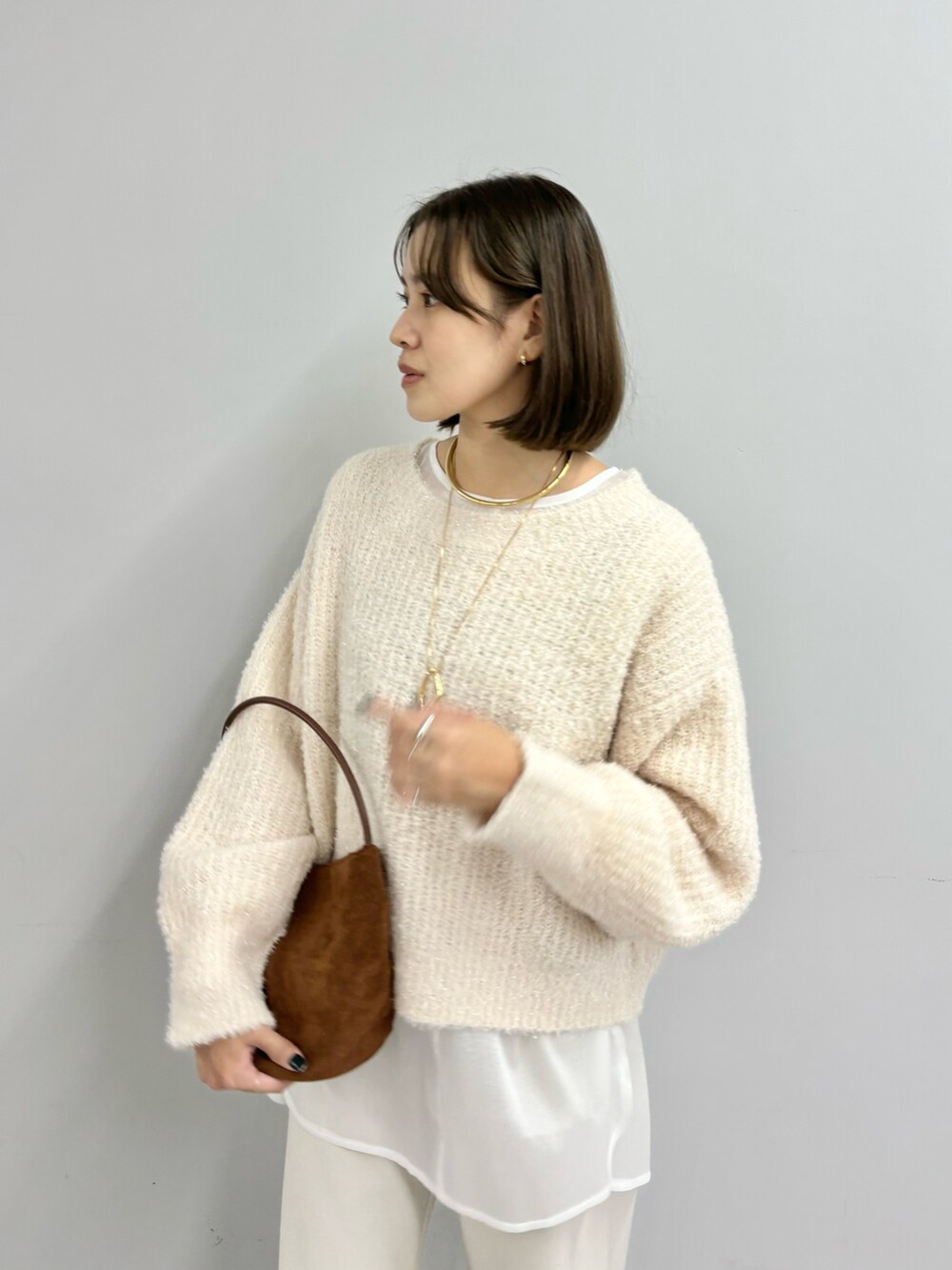 ブラウン系のトートバッグ、ホワイト系のニット/セーター、ホワイト系のシャツ/ブラウスを着用したレディースの冬コーディネートの3枚目の写真