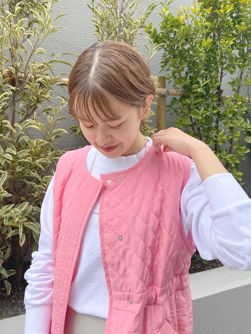 ホワイト系のスウェット、ピンク系のベスト、グレー系のスカートを着用したレディースの春コーディネートの4枚目の写真