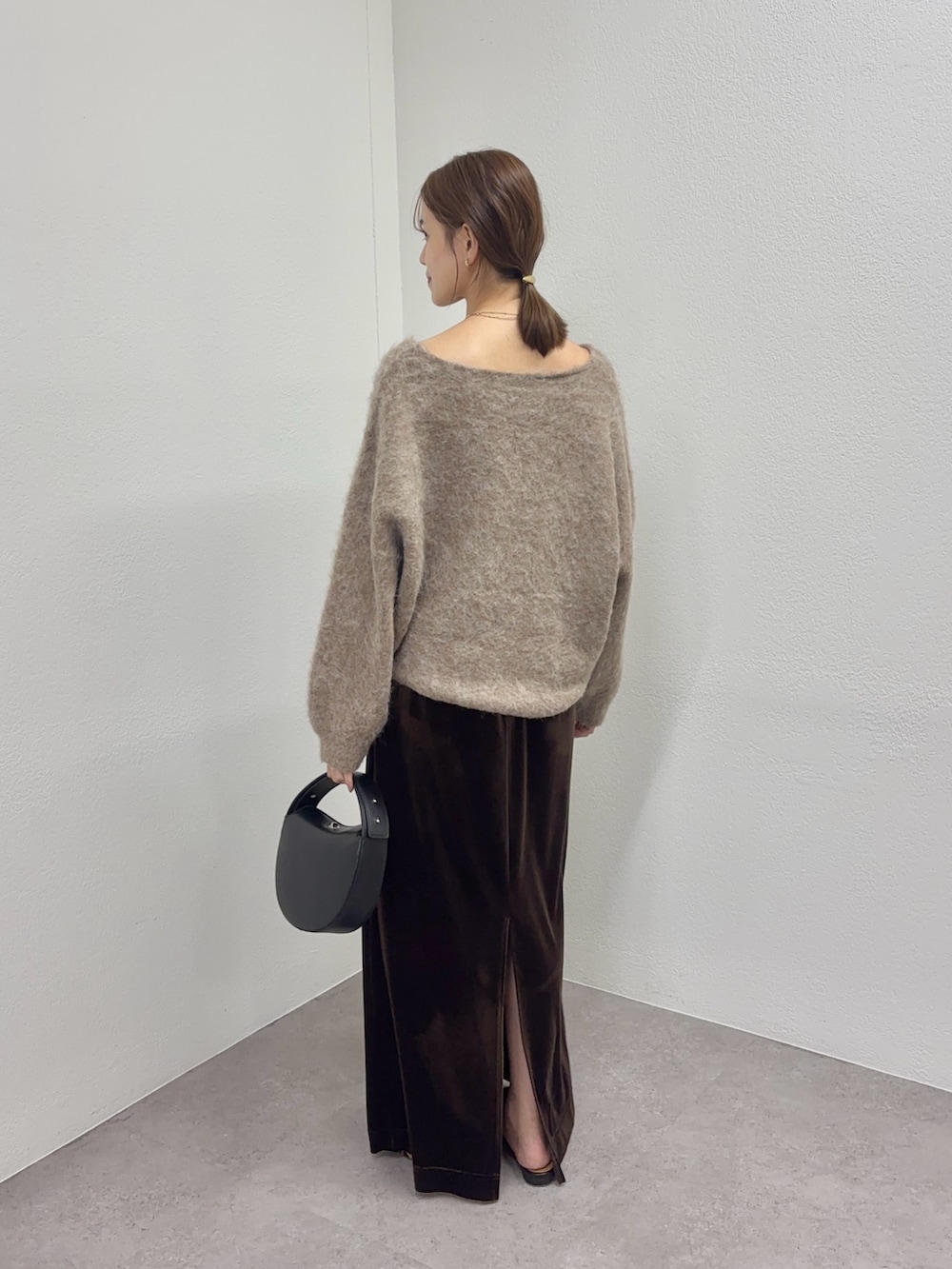ブラウン系のニット/セーター、ブラック系のトートバッグ、ブラウン系のスカートを着用したレディースの秋コーディネートの2枚目の写真