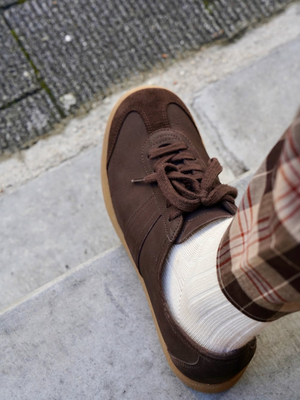 ブラウン系のスニーカー、ブラウン系のパンツ、ベージュ系のトートバッグを着用したメンズの春コーディネートの3枚目の写真