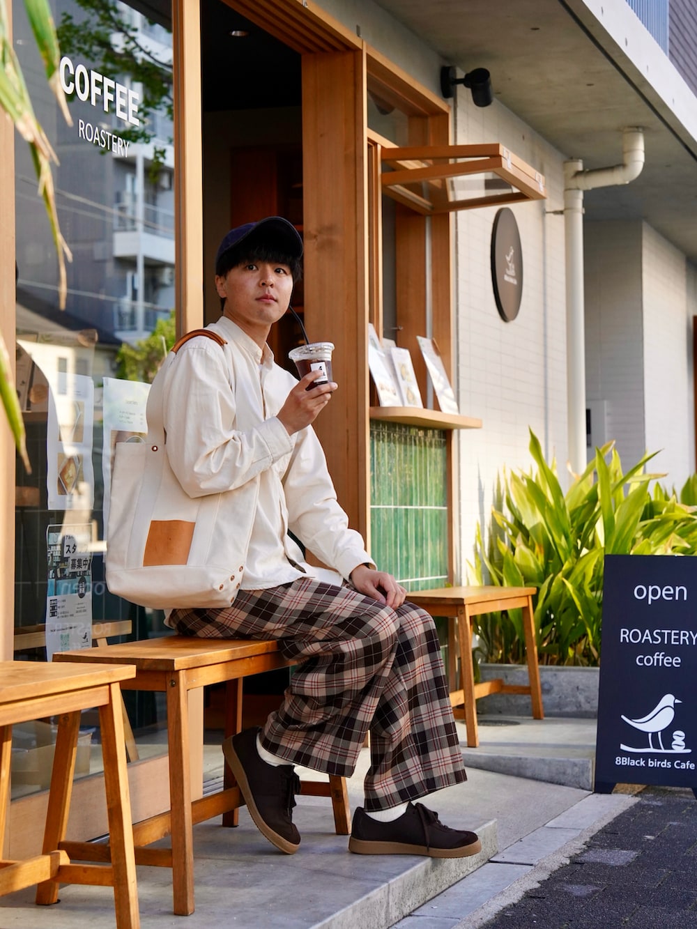 ブラウン系のスニーカー、ブラウン系のパンツ、ベージュ系のトートバッグを着用したメンズの春コーディネートの2枚目の写真