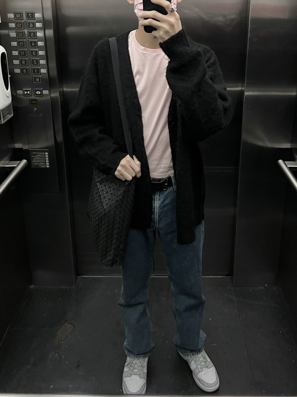 ブルー系のデニムパンツ、グレー系のスニーカー、ブラック系のカーディガン/ボレロを着用したメンズの冬コーディネートの2枚目の写真