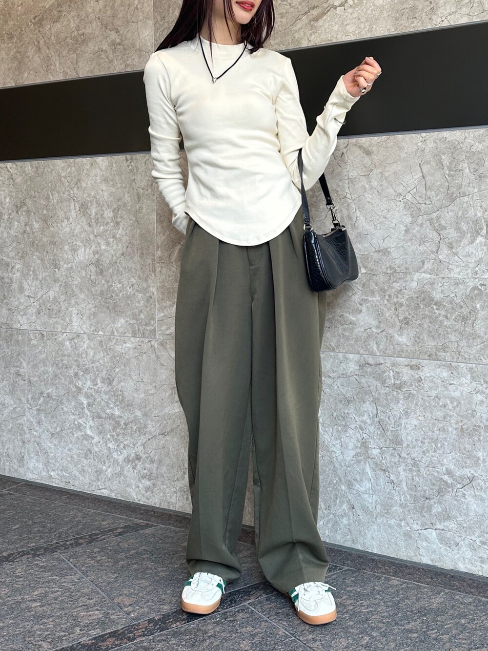 ブラック系のハンドバッグ、ホワイト系のTシャツ/カットソー、グリーン系のパンツを着用したレディースの春コーディネートの2枚目の写真