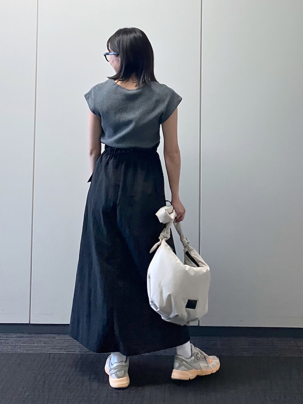 ブラック系のワンピース/ドレス、ホワイト系のバッグ、グレー系のスニーカーを着用したレディースの春コーディネートの2枚目の写真