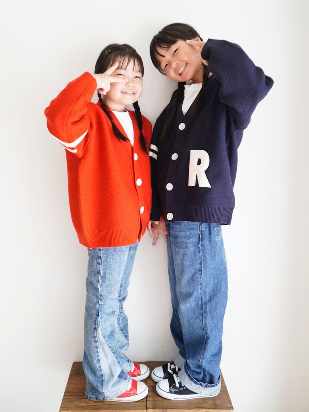 ブルー系のニット/セーター、レッド系のニット/セーター、ブルー系のデニムパンツを着用したキッズの秋コーディネートの2枚目の写真