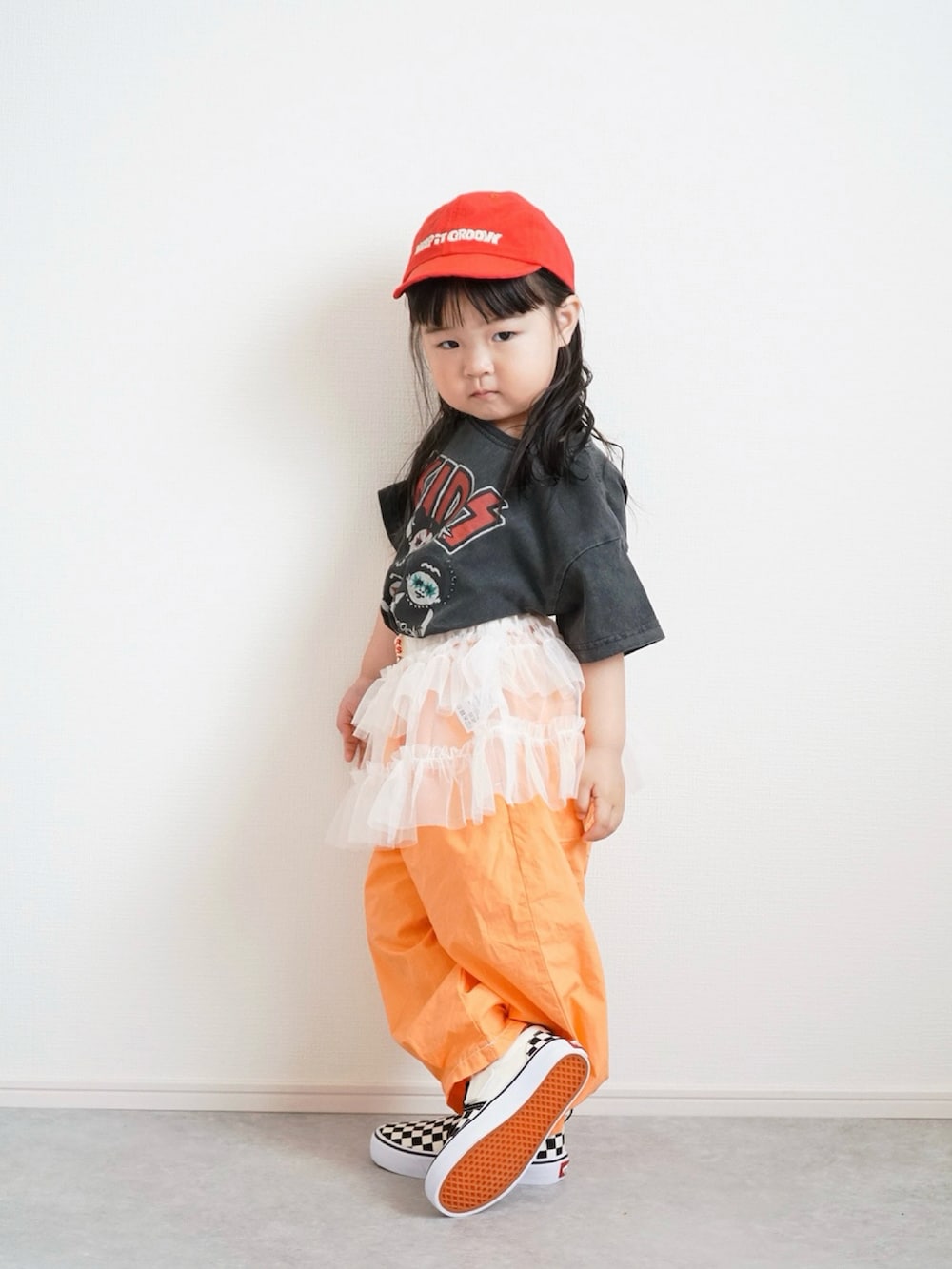 ブラック系のTシャツ/カットソー、オレンジ系のその他パンツ、ホワイト系のスカートを着用したキッズの春コーディネートの2枚目の写真