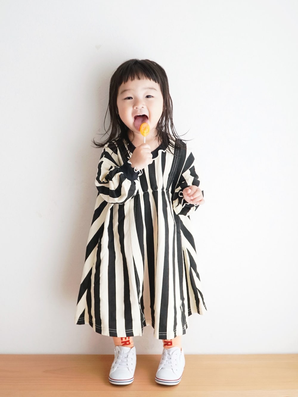 ホワイト系のスニーカー、ブラック系のワンピース、オレンジ系のタイツ/ストッキングを着用したキッズの秋コーディネートの3枚目の写真