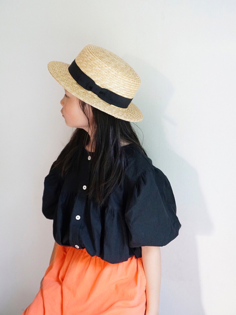 オレンジ系のスカート、ブラック系のサンダル、ブラック系のシャツ/ブラウスを着用したキッズの春コーディネートの3枚目の写真