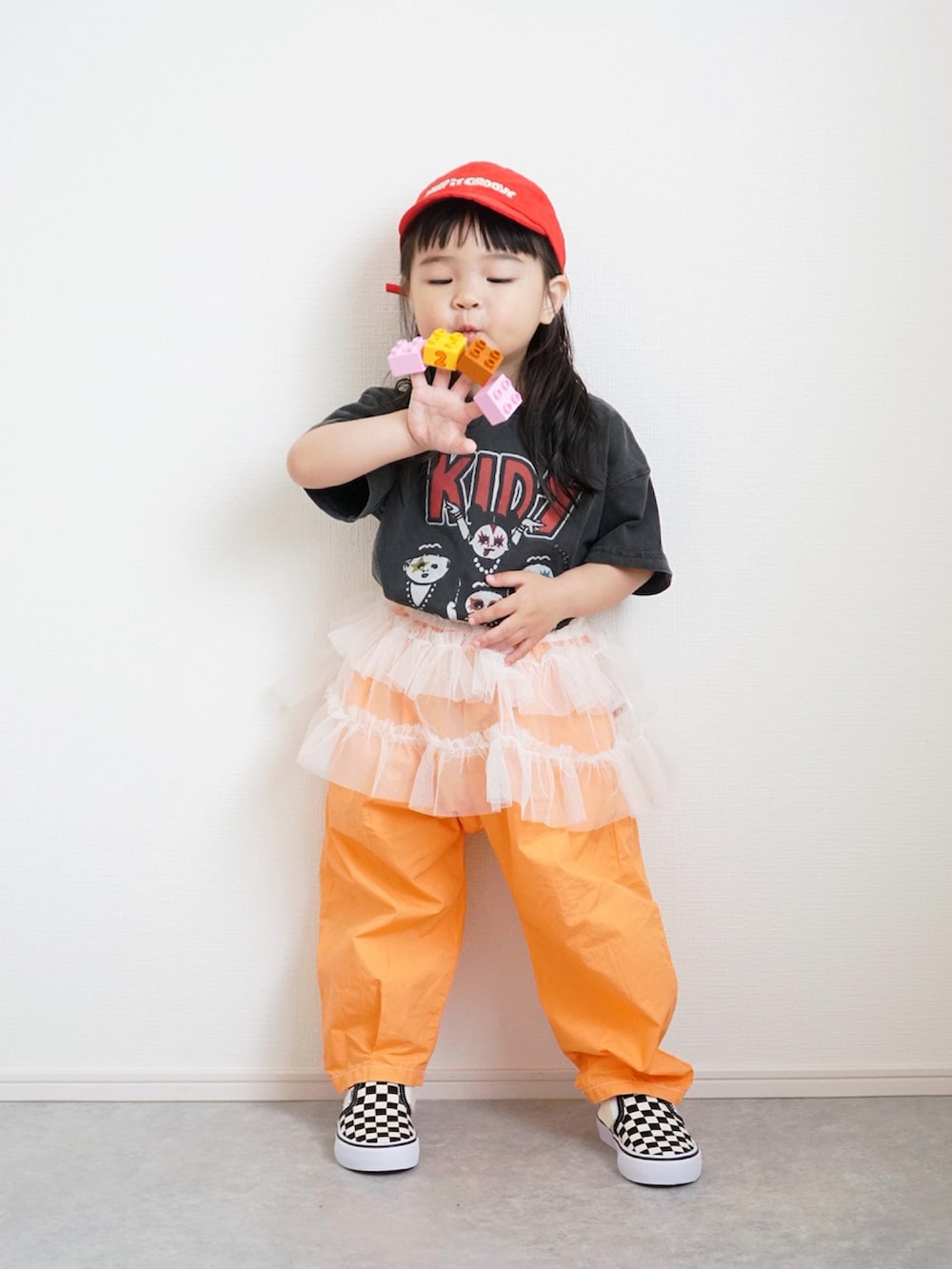 ブラック系のTシャツ/カットソー、オレンジ系のその他パンツ、ホワイト系のスカートを着用したキッズの春コーディネートの4枚目の写真