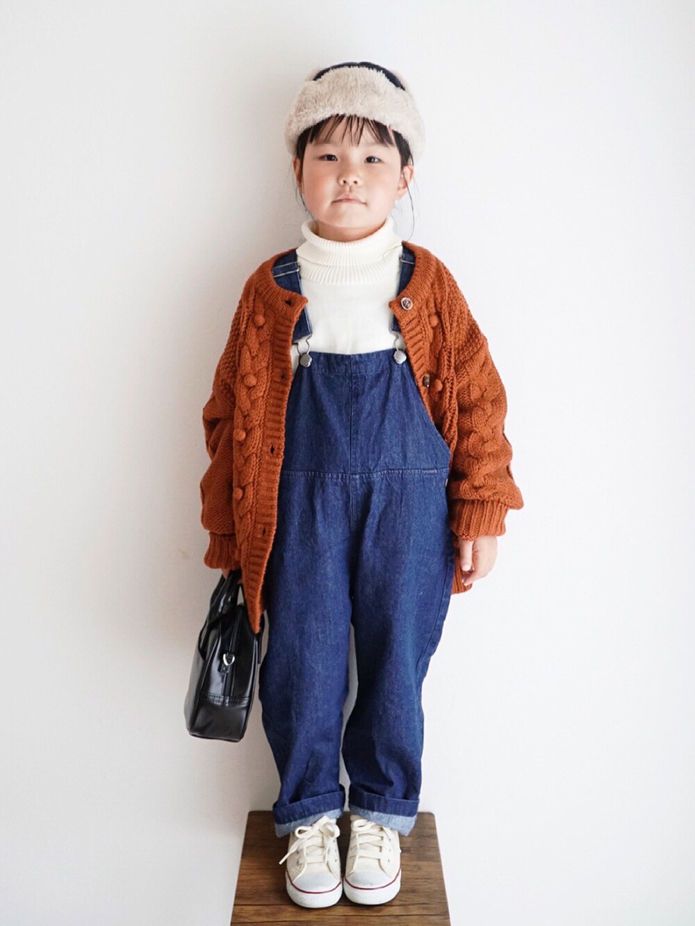 ホワイト系のニット/セーター、ブルー系のサロペット/オーバーオール、オレンジ系のカーディガン/ボレロを着用したキッズの秋コーディネートの3枚目の写真