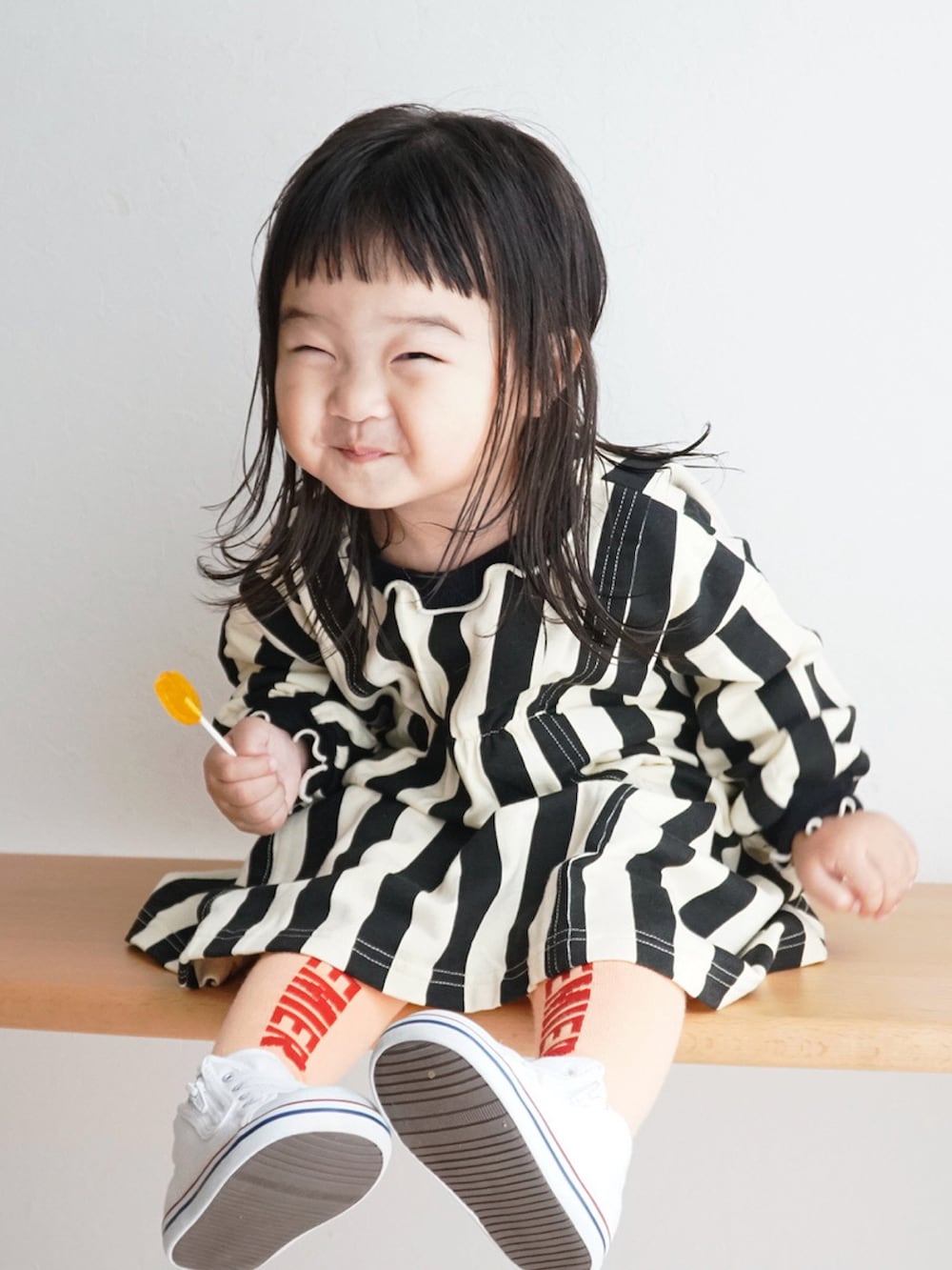 ホワイト系のスニーカー、ブラック系のワンピース、オレンジ系のタイツ/ストッキングを着用したキッズの秋コーディネートの2枚目の写真