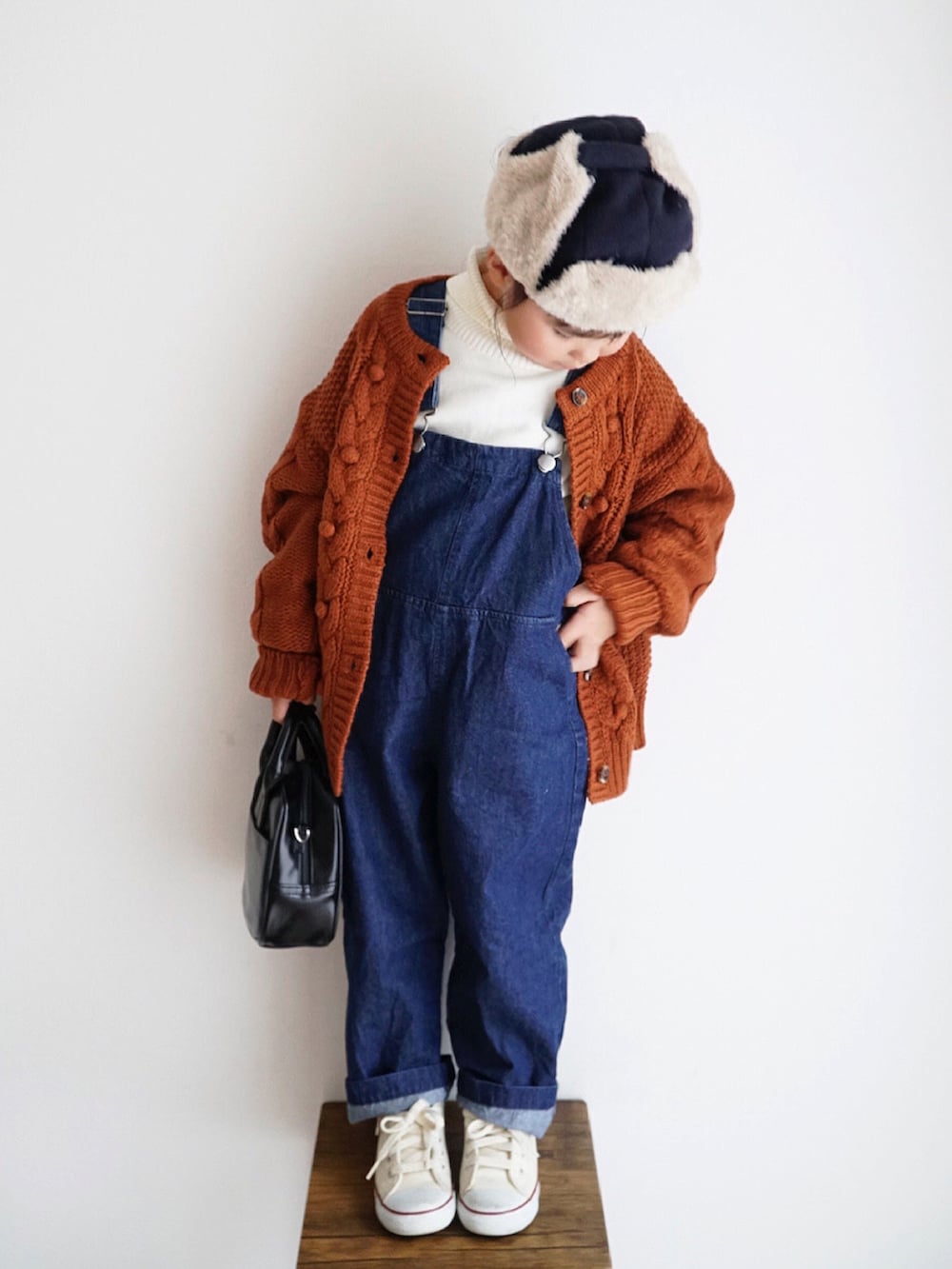 ホワイト系のニット/セーター、ブルー系のサロペット/オーバーオール、オレンジ系のカーディガン/ボレロを着用したキッズの秋コーディネートの4枚目の写真