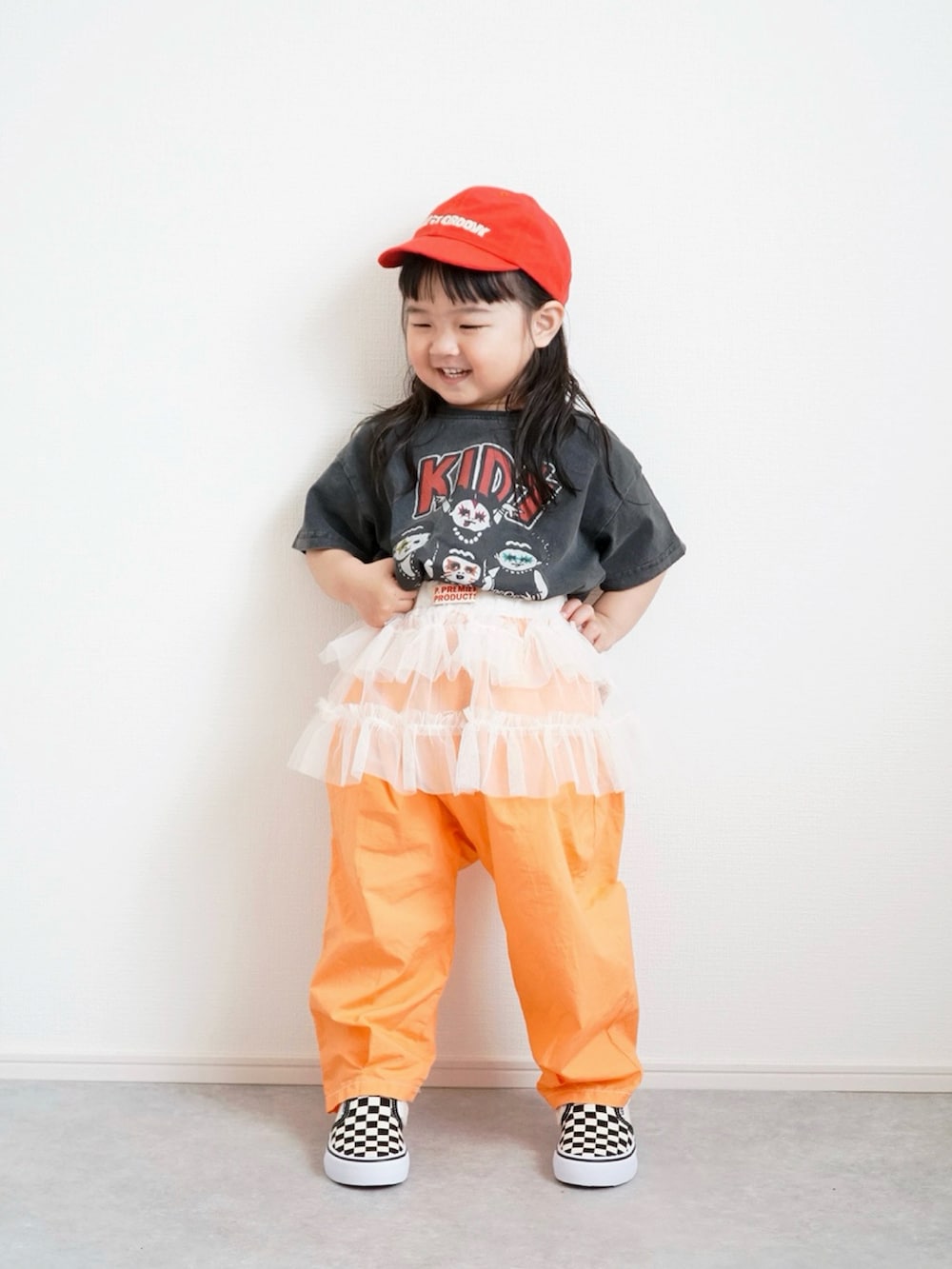 ブラック系のTシャツ/カットソー、オレンジ系のその他パンツ、ホワイト系のスカートを着用したキッズの春コーディネートの3枚目の写真