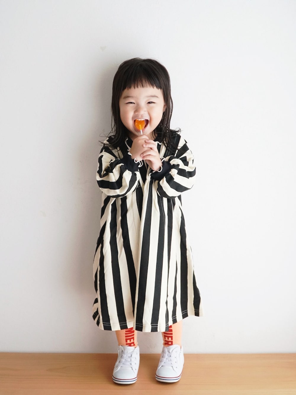 ホワイト系のスニーカー、ブラック系のワンピース、オレンジ系のタイツ/ストッキングを着用したキッズの秋コーディネートの5枚目の写真