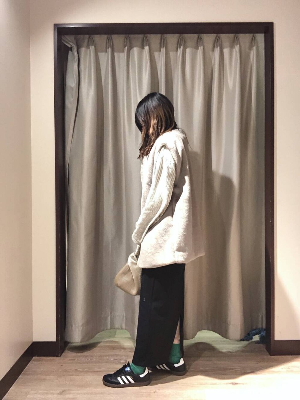 ゴールド系のハンドバッグ、ブラック系のスカート、ホワイト系のTシャツ/カットソーを着用したレディースの秋コーディネートの2枚目の写真