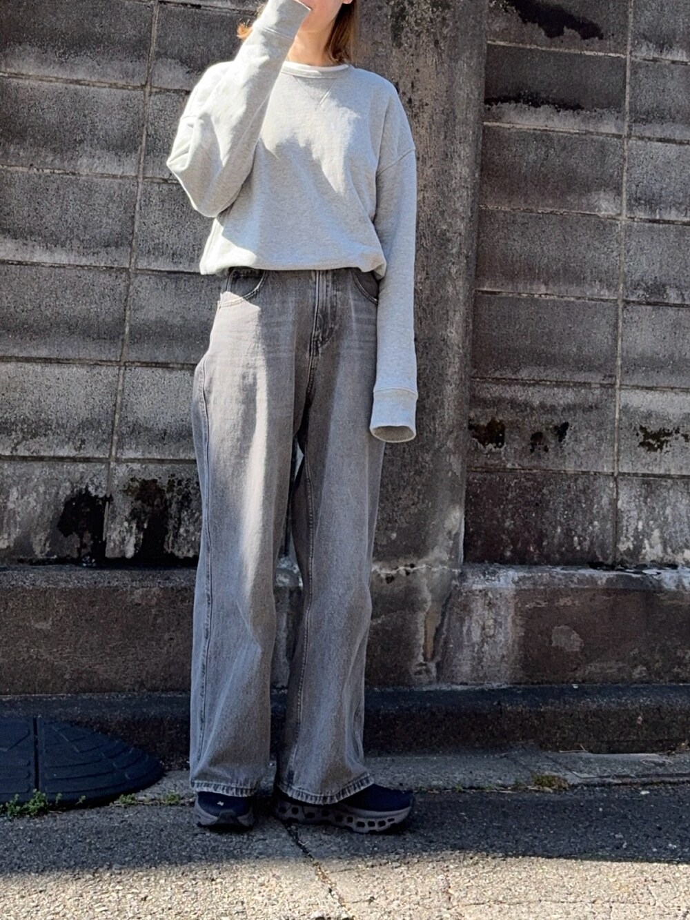 グレー系のデニムパンツ、グレー系のスウェット、ブラック系のスニーカーを着用したレディースの春コーディネートの4枚目の写真