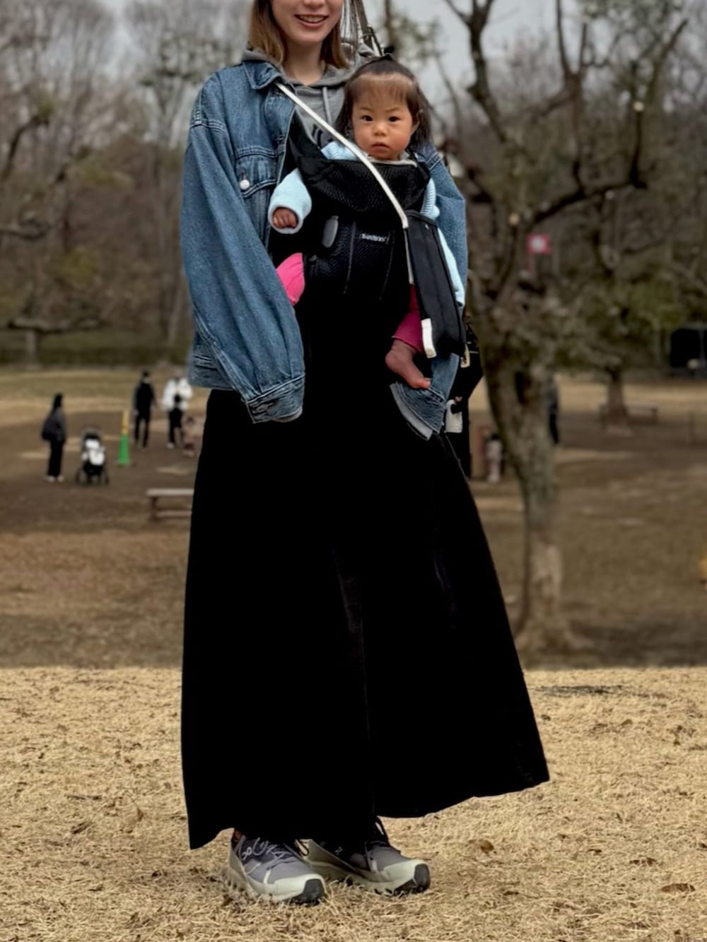 ブラック系のスカート、グレー系のスニーカー、ブルー系のデニムジャケットを着用したレディースの春コーディネートの2枚目の写真