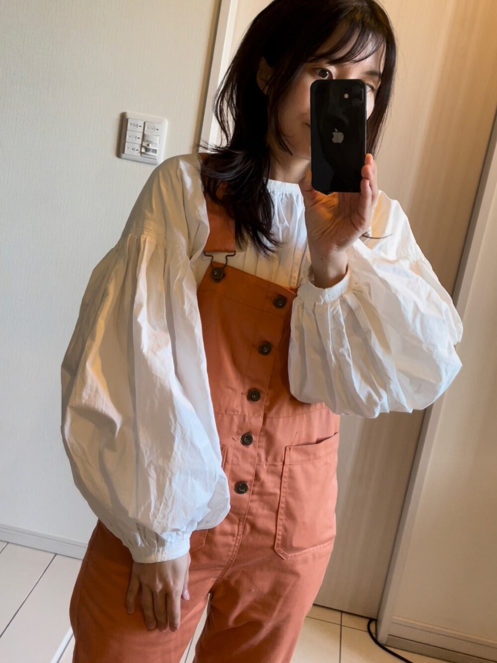 オレンジ系のサロペット/オーバーオール、ホワイト系のシャツ/ブラウス、ブラウン系のブーツを着用したレディースの春コーディネートの2枚目の写真