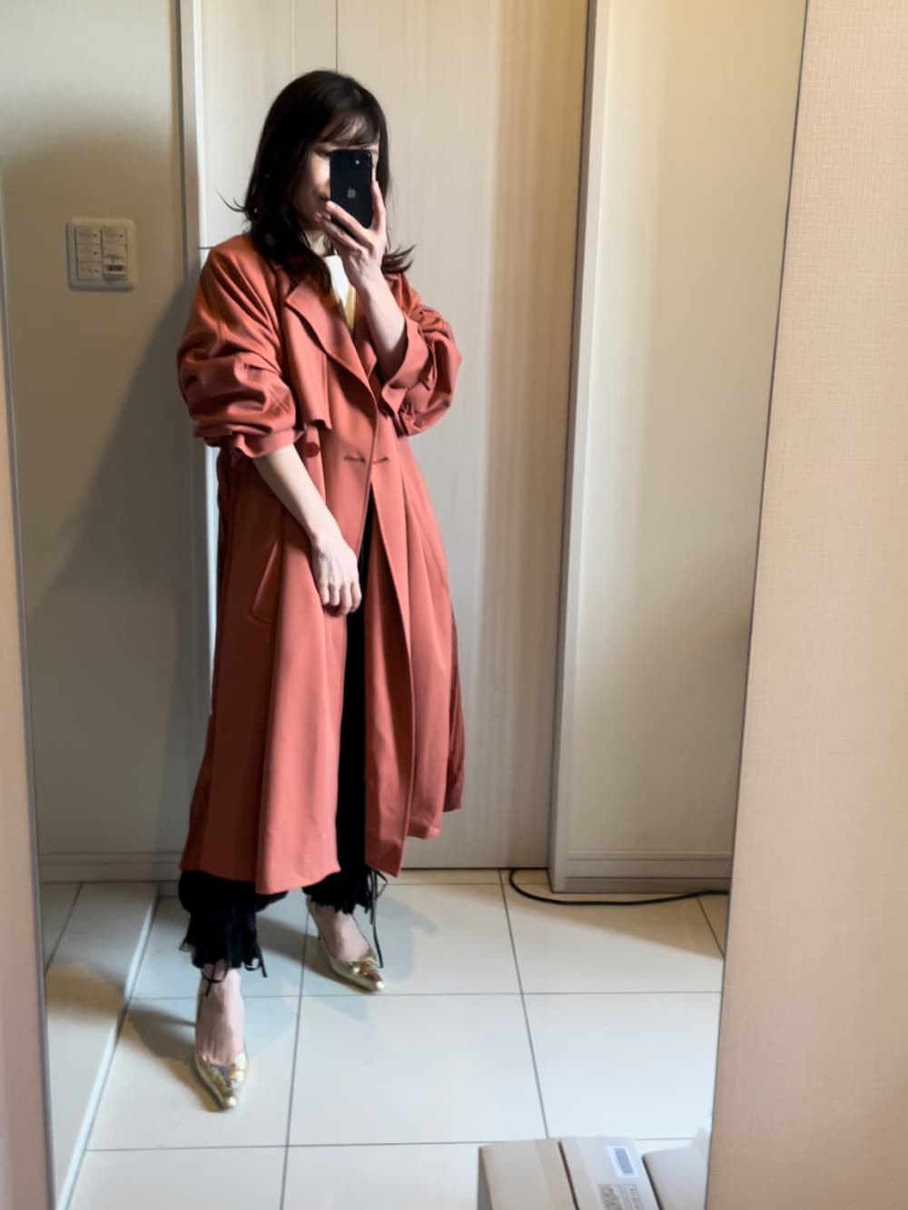 ゴールド系のパンプス、ブラウン系のトレンチコートを着用したレディースの春コーディネートの2枚目の写真