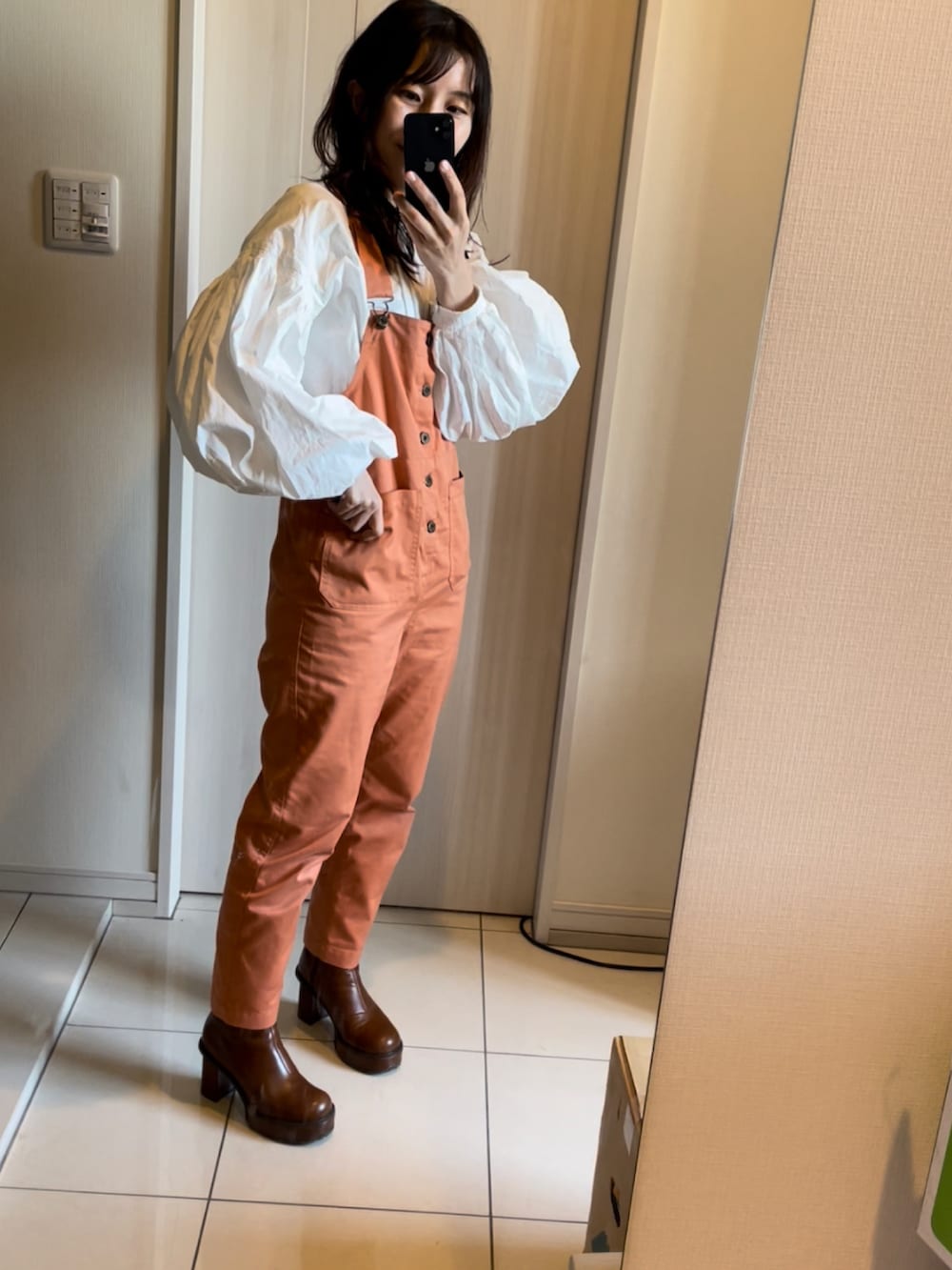 オレンジ系のサロペット/オーバーオール、ホワイト系のシャツ/ブラウス、ブラウン系のブーツを着用したレディースの春コーディネートの4枚目の写真
