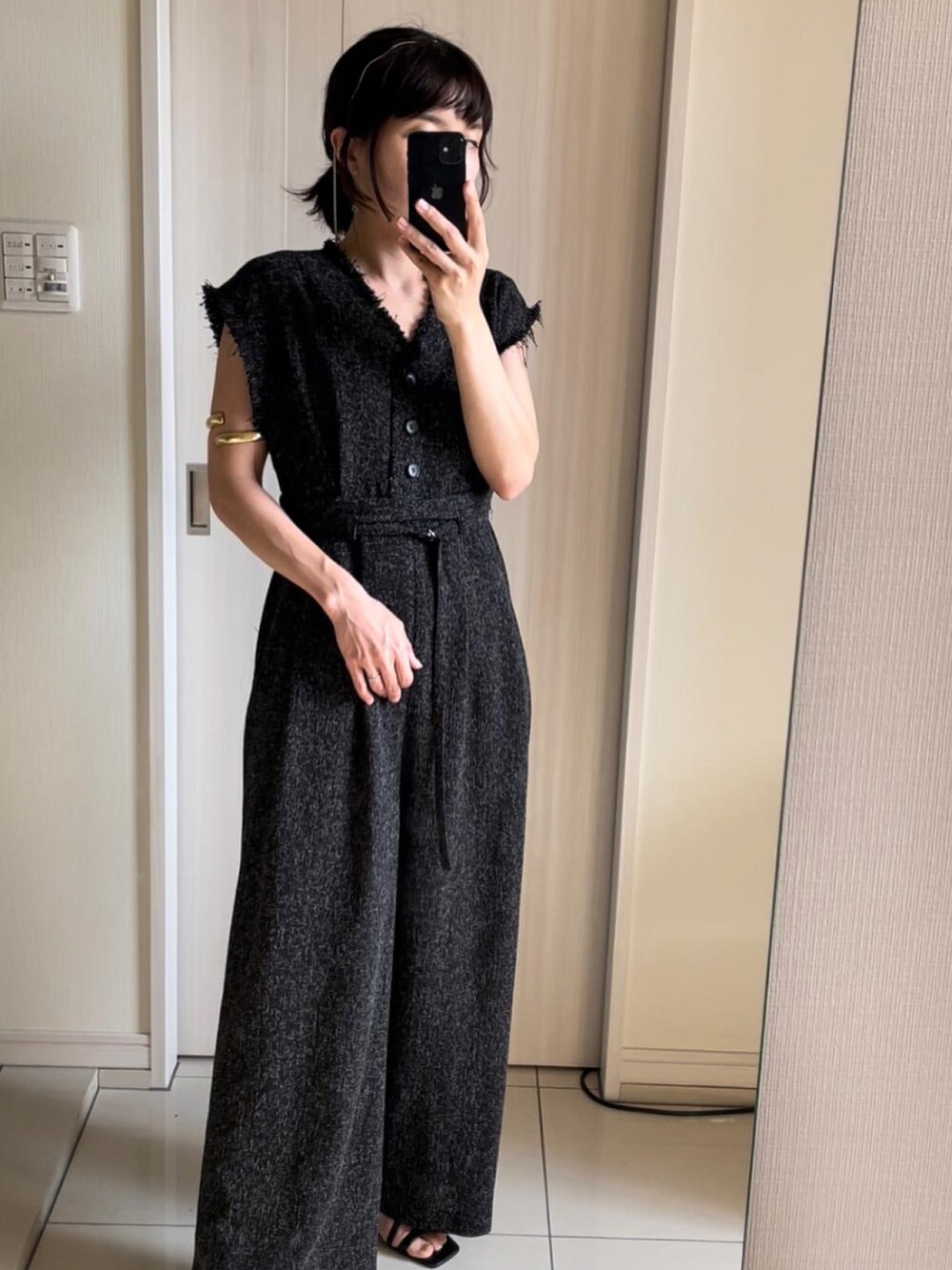 ブラック系のオールインワン・サロペット、ブラック系のサンダル、ゴールド系のバングル/リストバンドを着用したレディースの夏コーディネートの3枚目の写真