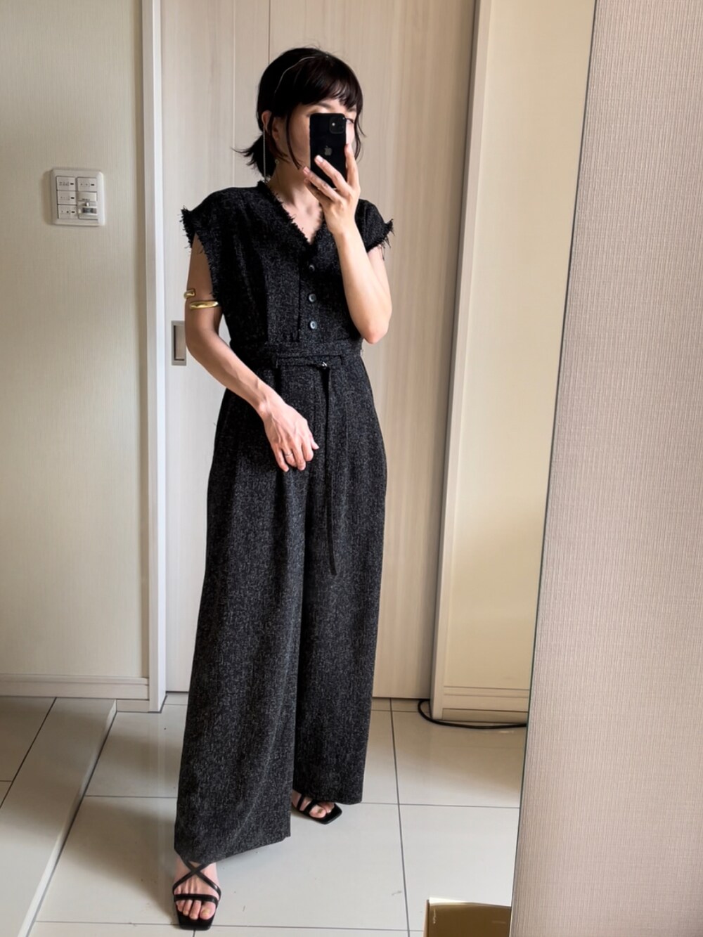 ブラック系のオールインワン・サロペット、ブラック系のサンダル、ゴールド系のバングル/リストバンドを着用したレディースの夏コーディネートの2枚目の写真