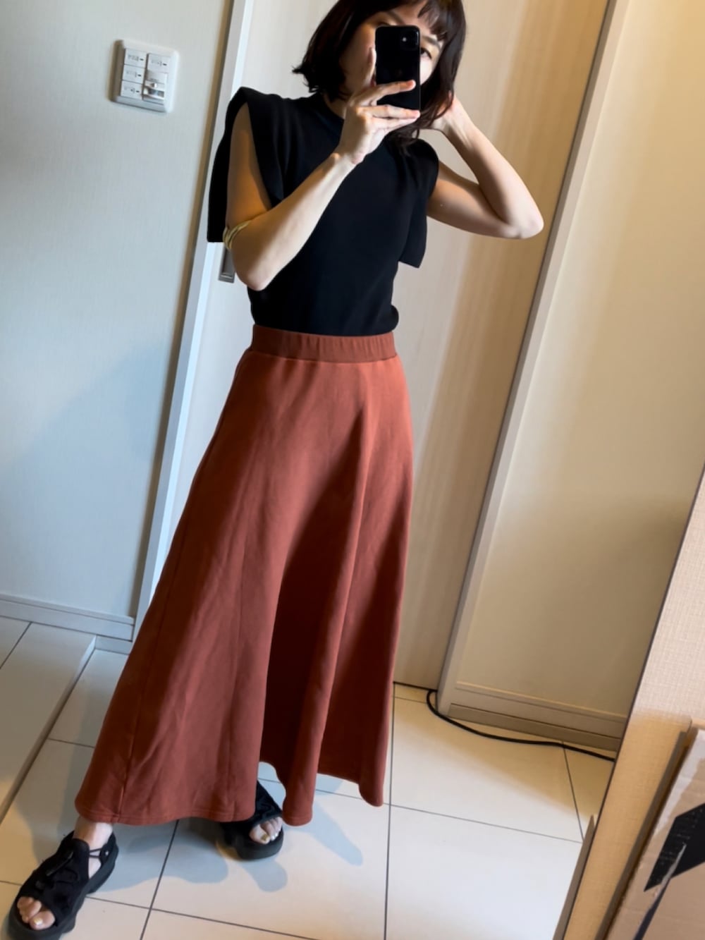 ブラック系のTシャツ/カットソー、ブラウン系のワンピース、ブラック系のサンダルを着用したレディースの春コーディネートの2枚目の写真