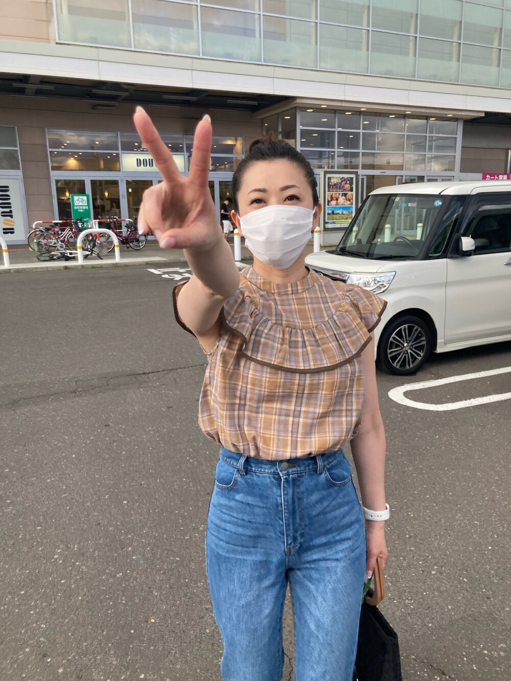 ベージュ系のシャツ/ブラウス、ブルー系のデニムパンツ、ブラック系のトートバッグを着用したレディースの夏コーディネートの2枚目の写真