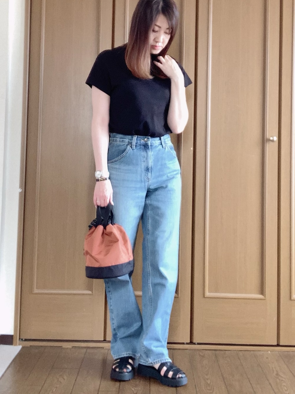 ブラック系のサンダル、ブルー系のデニムパンツ、ブラック系のTシャツ/カットソーを着用したレディースの夏コーディネートの2枚目の写真