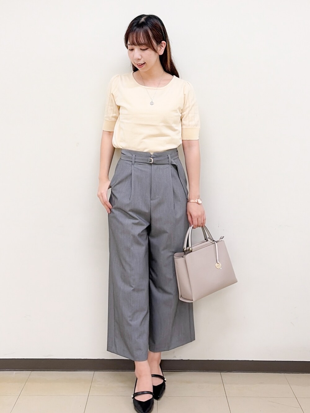 イエロー系のニット/セーター、グレー系のその他パンツ、ベージュ系のトートバッグを着用したレディースの秋コーディネートの7枚目の写真