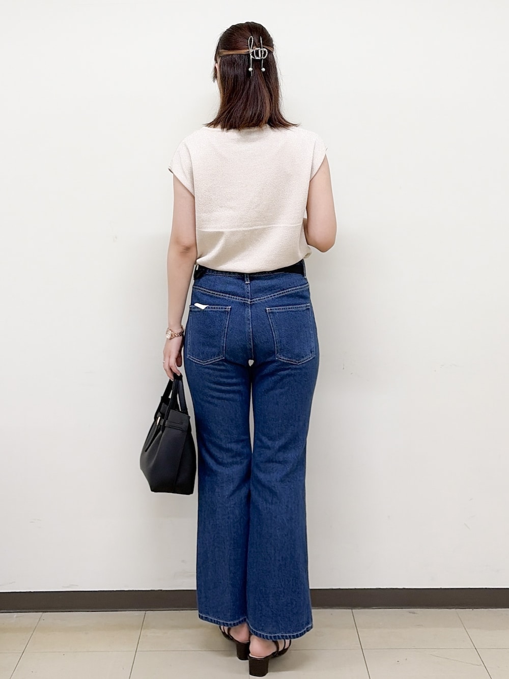 ピンク系のニット/セーター、ブルー系のデニムパンツ、ブラック系のトートバッグを着用したレディースの夏コーディネートの3枚目の写真