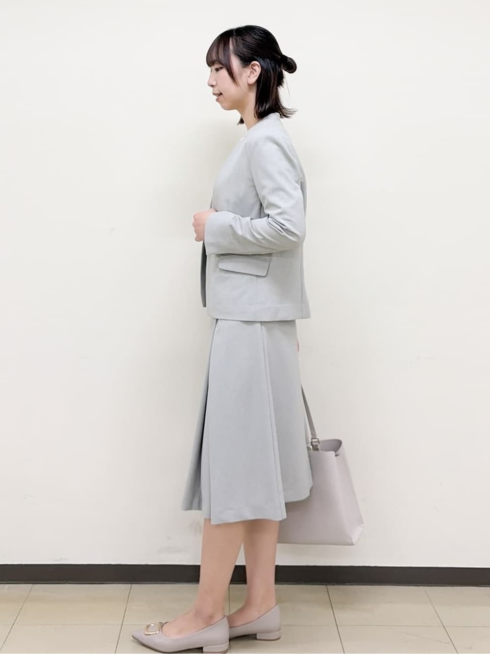 ベージュ系のパンプス、グレー系のスカート、グレー系のノーカラージャケットを着用したレディースの春コーディネートの3枚目の写真