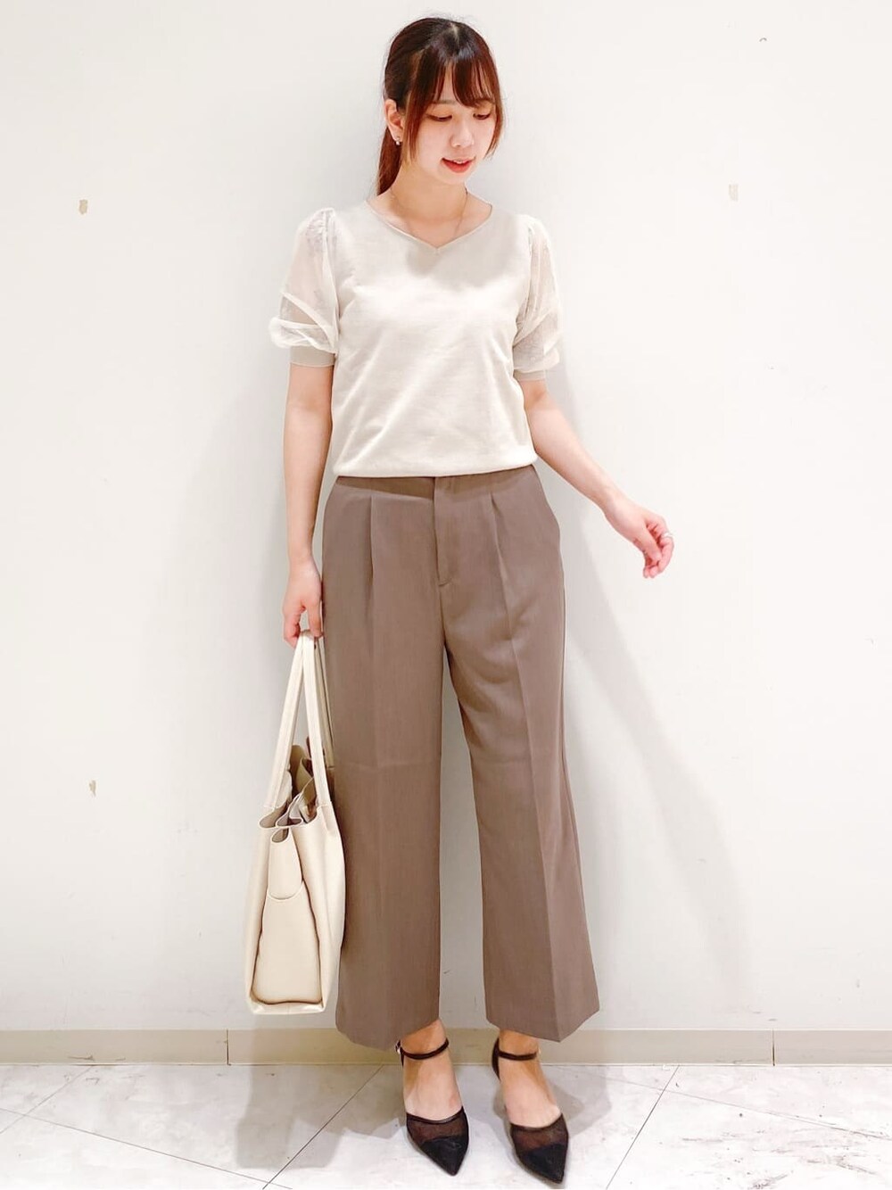 ベージュ系のニット/セーター、ブラウン系のその他パンツ、ホワイト系のトートバッグを着用したレディースの夏コーディネートの4枚目の写真