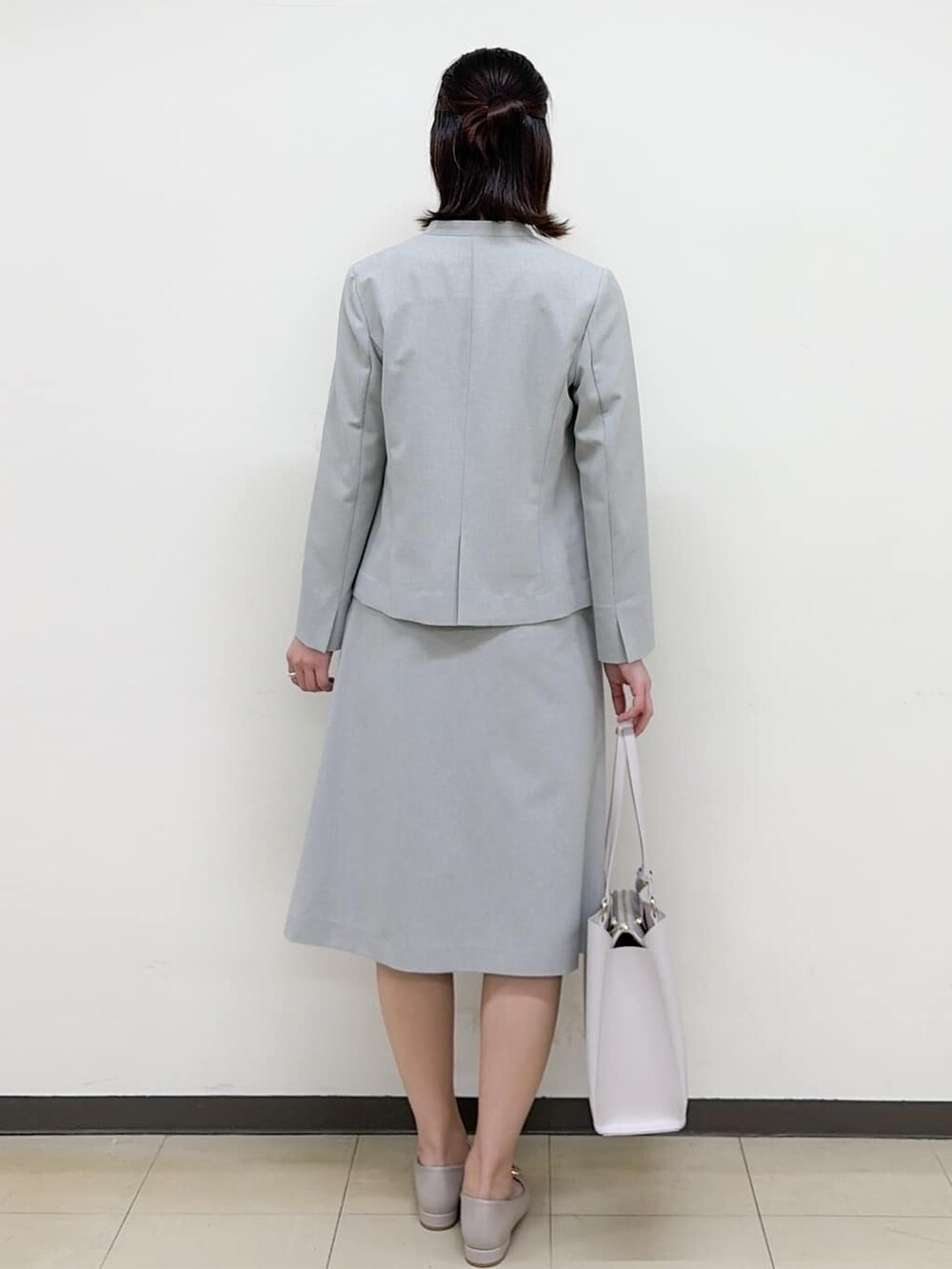 ベージュ系のパンプス、グレー系のスカート、グレー系のノーカラージャケットを着用したレディースの春コーディネートの4枚目の写真
