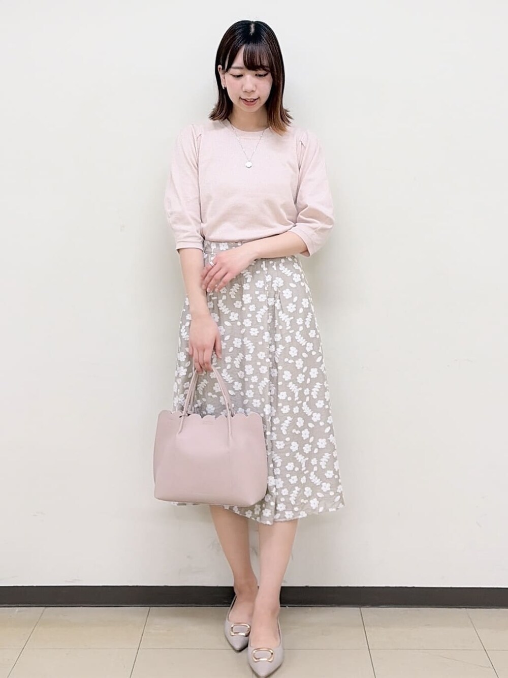 ベージュ系のパンプス、ベージュ系のスカート、ピンク系のニット/セーターを着用したレディースの春コーディネートの2枚目の写真