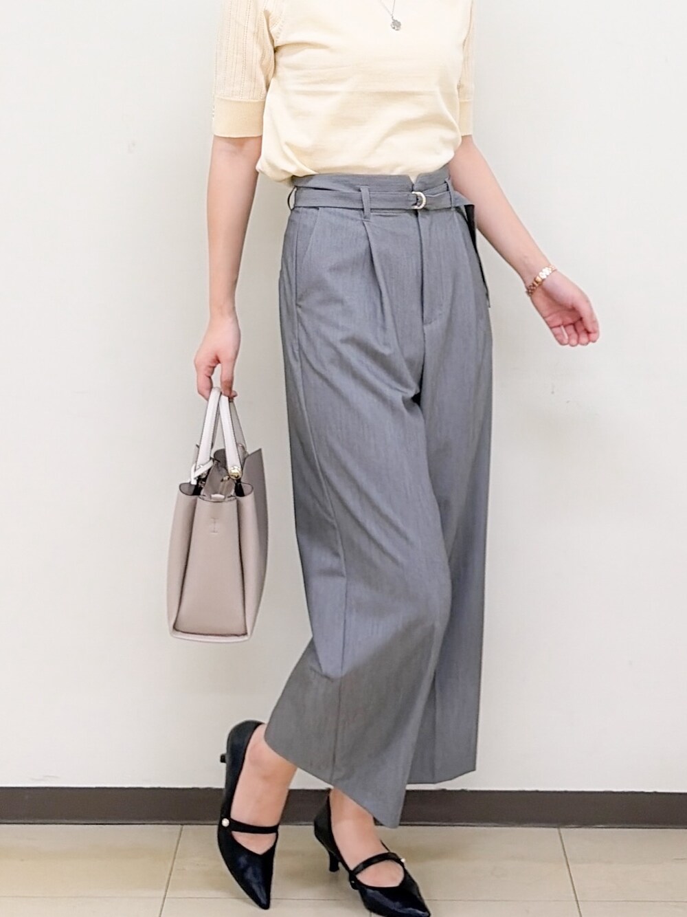 イエロー系のニット/セーター、グレー系のその他パンツ、ベージュ系のトートバッグを着用したレディースの秋コーディネートの2枚目の写真