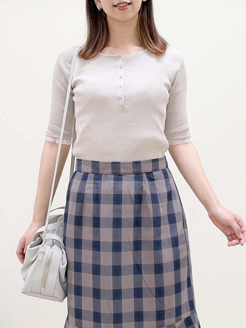 ベージュ系のニット/セーター、ブラウン系のスカート、グレー系のボストンバッグを着用したレディースの夏コーディネートの5枚目の写真