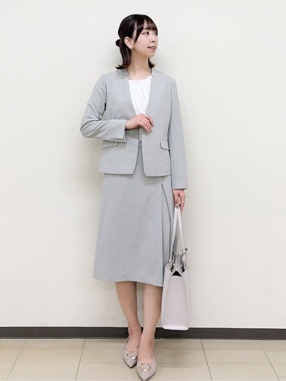 ベージュ系のパンプス、グレー系のスカート、グレー系のノーカラージャケットを着用したレディースの春コーディネートの5枚目の写真