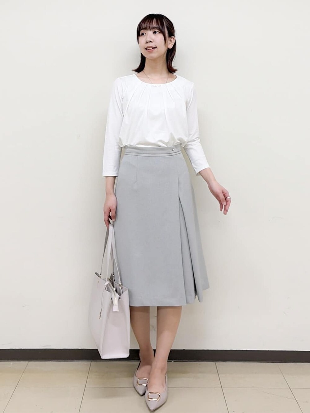 ベージュ系のパンプス、グレー系のスカート、グレー系のノーカラージャケットを着用したレディースの春コーディネートの6枚目の写真