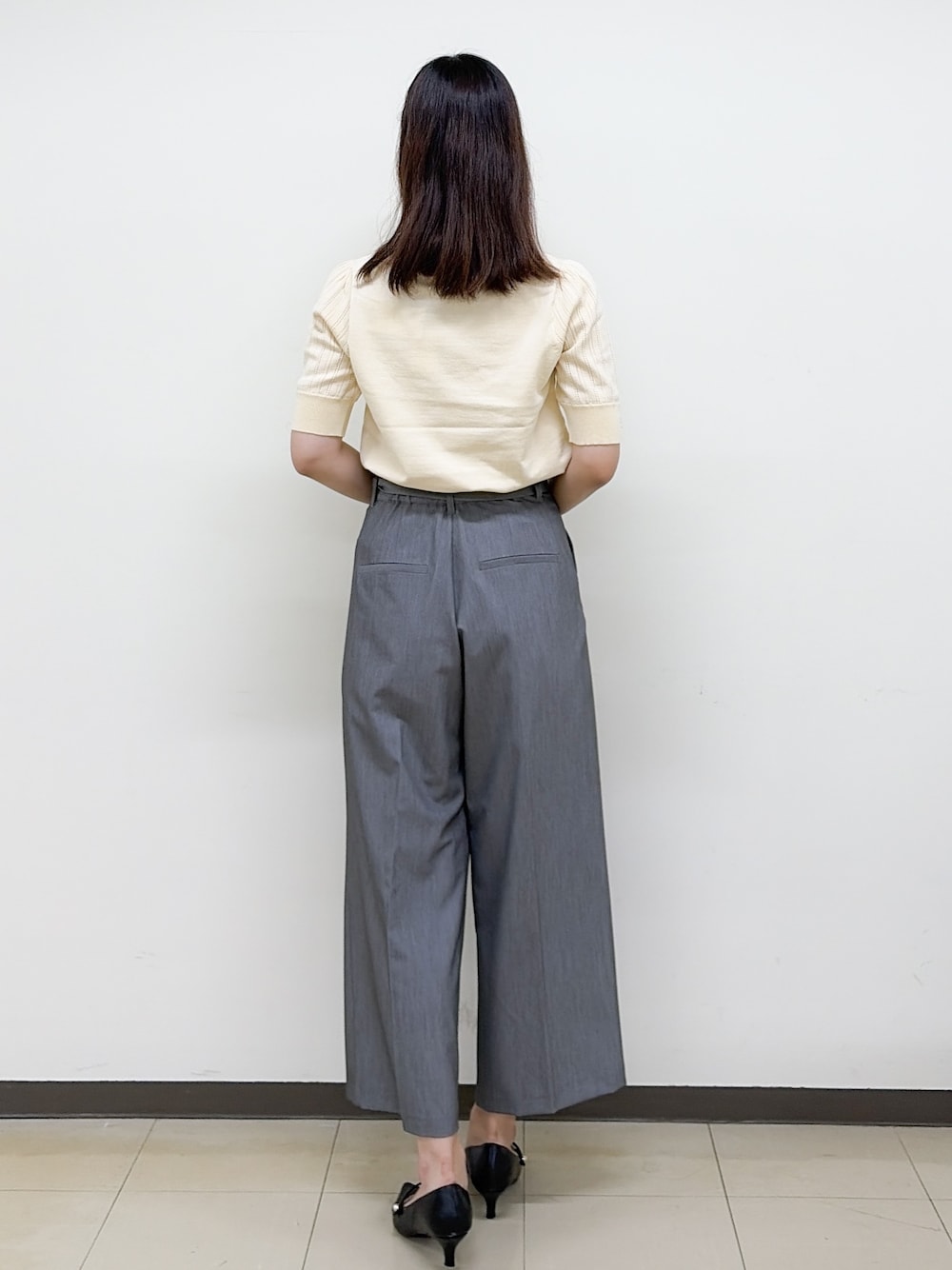 イエロー系のニット/セーター、グレー系のその他パンツ、ベージュ系のトートバッグを着用したレディースの秋コーディネートの4枚目の写真