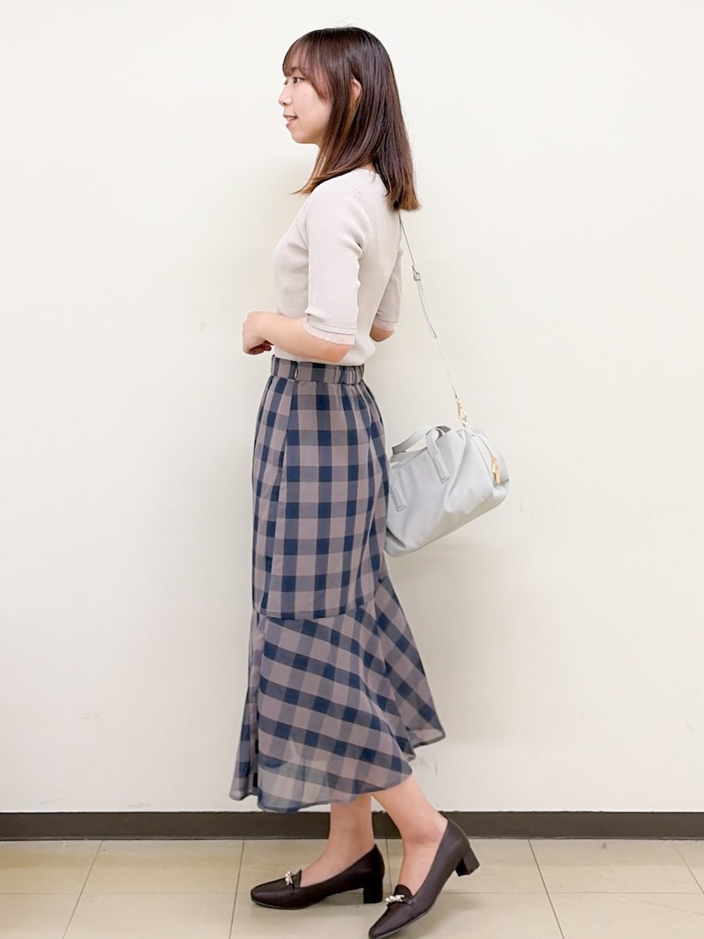 ベージュ系のニット/セーター、ブラウン系のスカート、グレー系のボストンバッグを着用したレディースの夏コーディネートの3枚目の写真