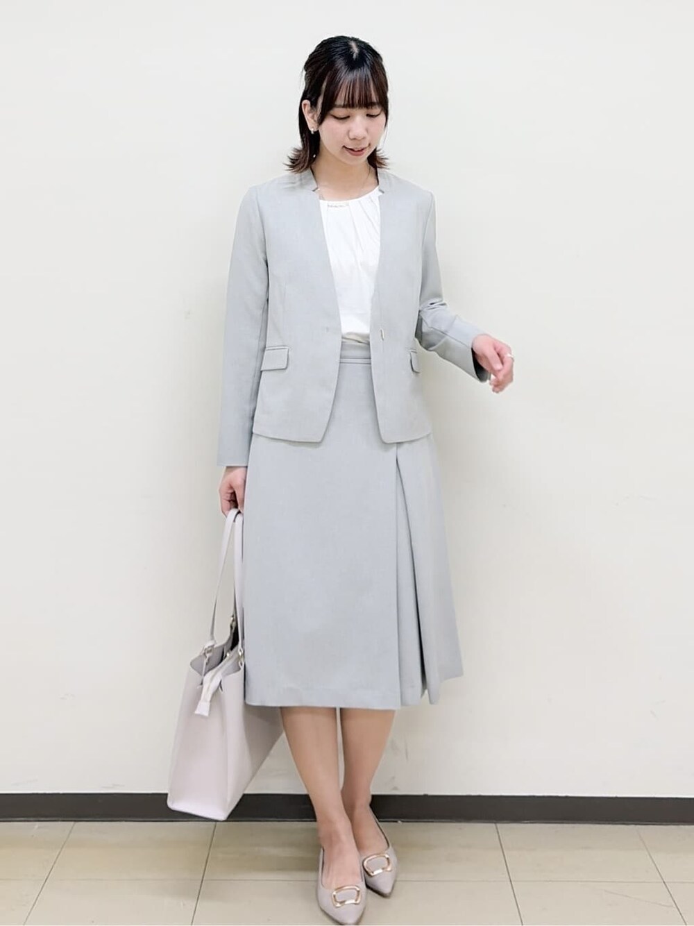 ベージュ系のパンプス、グレー系のスカート、グレー系のノーカラージャケットを着用したレディースの春コーディネートの2枚目の写真