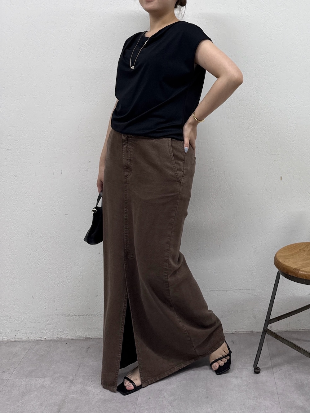 ブラウン系のスカート、ブラック系のサンダル、ブラック系のTシャツ/カットソーを着用したレディースの夏コーディネートの2枚目の写真