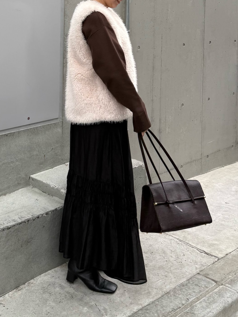 ブラック系のスカート、ブラック系のブーツ、ブラウン系のニット/セーターを着用したレディースの秋コーディネートの2枚目の写真