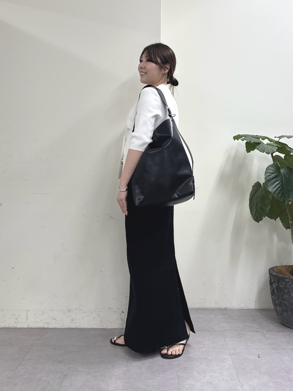 ブラック系のスカート、ホワイト系のカーディガン/ボレロ、ブラック系のショルダーバッグを着用したレディースの春コーディネートの2枚目の写真