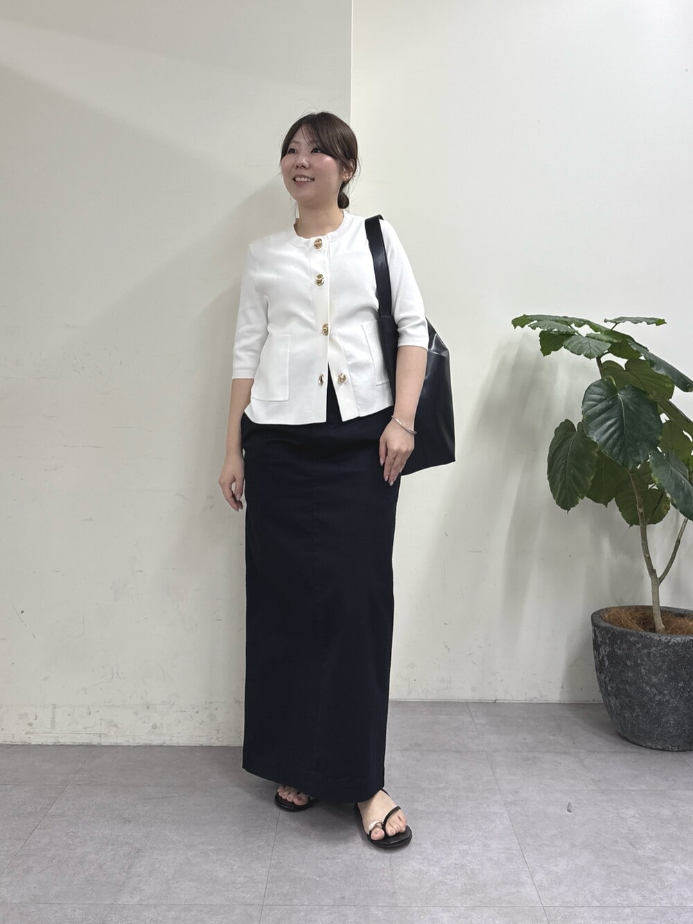 ブラック系のスカート、ホワイト系のカーディガン/ボレロ、ブラック系のショルダーバッグを着用したレディースの春コーディネートの4枚目の写真