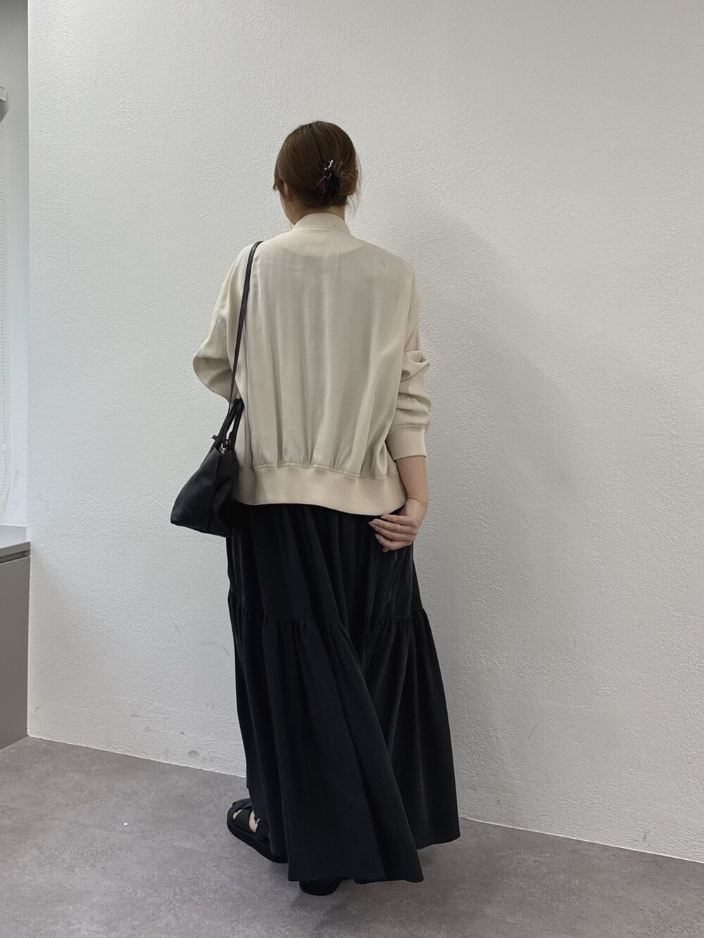 グレー系のワンピース、ブラック系のサンダル、ベージュ系のブルゾンを着用したレディースの春コーディネートの2枚目の写真