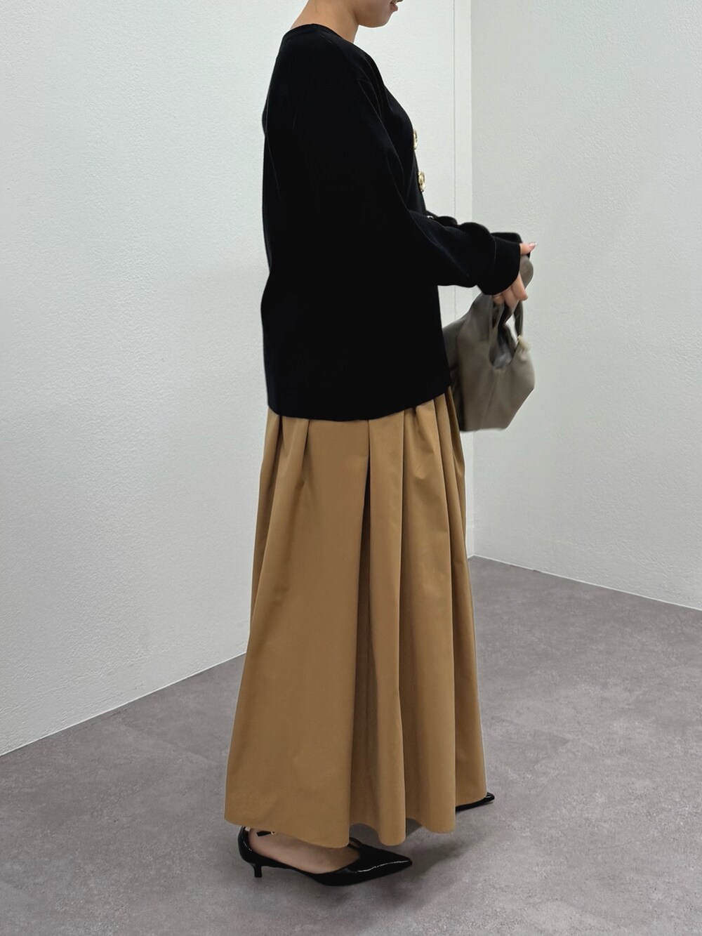 ブラック系のパンプス、イエロー系のスカート、ベージュ系のトートバッグを着用したレディースの冬コーディネートの4枚目の写真