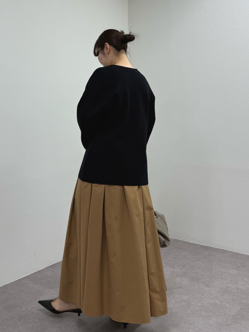 ブラック系のパンプス、イエロー系のスカート、ベージュ系のトートバッグを着用したレディースの冬コーディネートの2枚目の写真