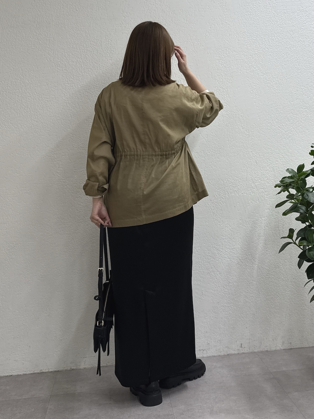 ブラック系のスカート、グリーン系のその他アウター、ホワイト系のTシャツ/カットソーを着用したレディースの冬コーディネートの3枚目の写真